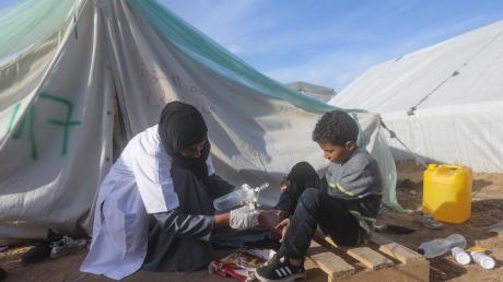Eine palästinensische Ärztin behandelt einen Jungen vor einem Zelt in Rafah.