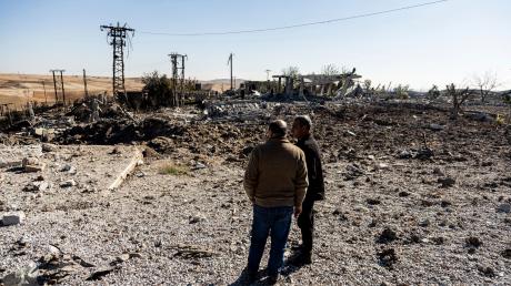 Zwei Männer begutachten Schäden in einem Gebiet um ein Elektrizitätswerk nach türkischen Luftangriffen.
