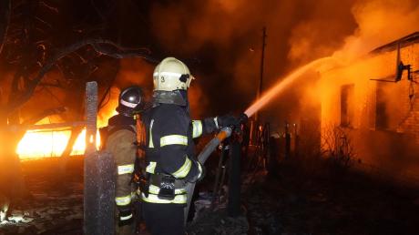 Feuerwehrleute löschen ein Feuer nach einem russischen Angriff auf ein Wohnviertel in Charkiw.