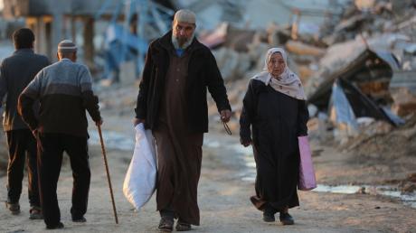 Menschen gehen an zerstörten Gebäuden im Flüchtlingslager Al-Maghazi im Zentrum des Gazastreifens vorbei. Das Bangen um eine Feuerpause vor Ramadan geht weiter.