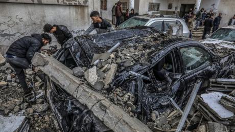 Palästinenser inspizieren zerstörte Fahrzeuge nach einem israelischen Luftangriff.