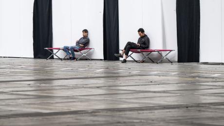 Geflüchtete sitzen auf Feldbetten in einer Massenunterkunft in Frankfurt: Viele Geflüchtete wünschen sich mehr Hilfe in Asyl- und Flüchtlingsfragen.