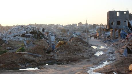 Menschen gehen an Trümmern und Ruinen auf einer Straße im Flüchtlingslager Al-Maghazi im Zentrum des Gazastreifens vorbei.