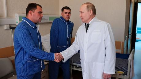 Russlands Präsident Wladimir Putin (r.) während eines Besuchs von verletzten Gefreiten im zentralen Militärkrankenhaus in Moskau.