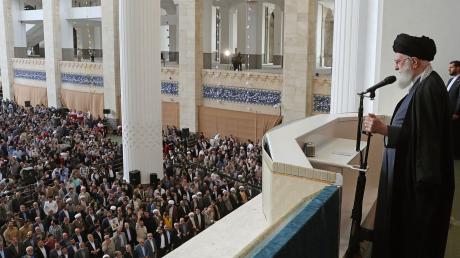Ajatollah Ali Chamenei hält bei seiner Rede den Lauf eines Gewehrs in der Hand.