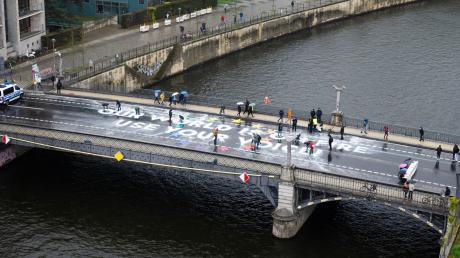 Klimaaktivisten der Bewegung Fridays for Future malen auf der Marschallbrücke in Berlin den Schriftzug «Our world is on fire - use your voice!».