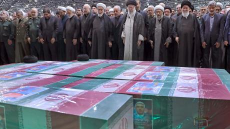 Abschied von Präsident Ebrahim Raisi, Außenminister Hussein Amirabdollahian und den weiteren beim Hubschrauberabsturz Getöteten: Irans Religionsführer Ajatollah Ali Chamenei (M.r.) spricht in Teheran an den mit Flaggen bedeckten Särgen ein Gebet.