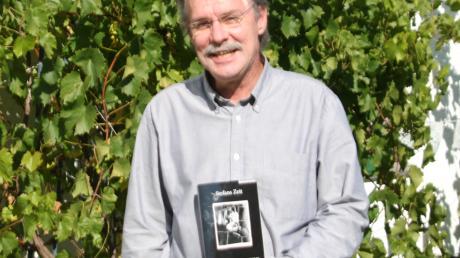 Bernhard Decker mit einer Ausgabe seines Buches „Stefans Zeit“ in seinem Garten.