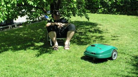 Rasenroboter bei der Arbeit – Siesta unter dem Baum für den Besitzer – doch Vorsicht auf die Füße! 
