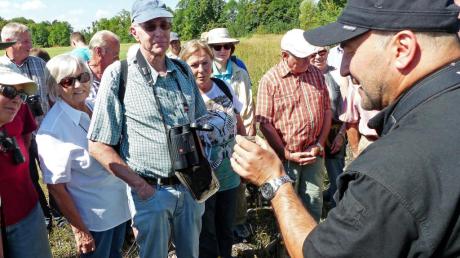 Richard Engelschall (rechts) erläutert Teilnehmern einer Exkursion die Eigenarten von Heuschrecken anhand eines gefangenen Exemplars. 