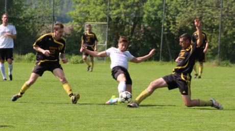 Der Fußball-Jargon spricht vom „langen Bein“: Megesheims Torschütze Patrick Hauswirth (in Weiß) gegen zwei Akteure des SV Hausen-Schopflohe.  
