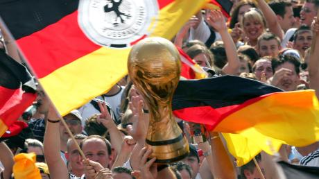 Deutschland im Sommer 2006: Fans schwenken Fahnen und jubeln einer Nachbildung des WM-Pokals auf der Fanmeile in Berlin zu.