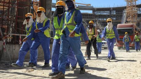 Ausländische Bauarbeiter verlassen eine Baustelle.