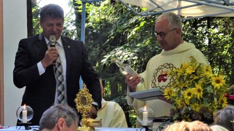 Mit einer Flasche hochprozentigem Laugnawasser wurde Pater Tomasz von Bürgermeister Johann Gebele zum zehnjährigen Wirken beschenkt. 	
