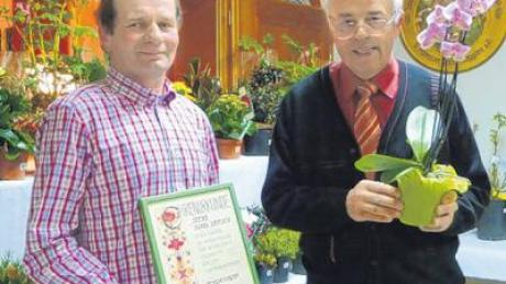 Alois Christa (links) ist nun Ehrenmitglied beim Gartenbauverein Binswangen. Vorsitzender Franz Endres überreichte zusätzlich eine Orchidee. Blumen von der Tombola (im Hintergrund) konnten die Gäste mit nach Hause nehmen. 