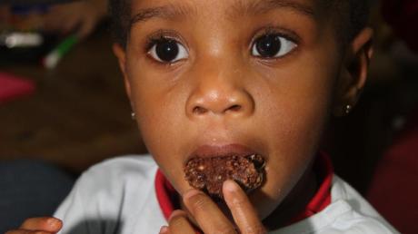 Wie das Plätzchen wohl schmeckt? Vorsichtig beißt dieser nigerianische Junge in eine Schokomakrone.