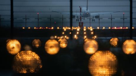 Ein Flugzeug landet hinter Signallichtern auf dem Flughafen Frankfurt. Die Flughafengesellschaft Fra