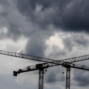 Baukräne vor dunklen Wolken. Fachleuten zufolge wird Deutschland im kommenden Jahr in die Rezession rutschen.
