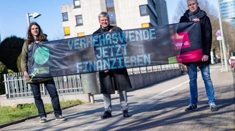 Emil Görtzen (l-r) von Fridays for Future, Jürgen Schirmer von Verdi und Patrick Steinbach vom Verkehrsbetrieb BoGeStra stehen mit einem Banner zum gemeinsamen Aktionstag vor der Verdi-Zentrale in Bochum.