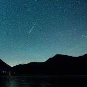 Eine Sternschnuppe leuchtet neben der Milchstraße am Himmel über dem Walchensee: Kann man die Geminiden 2022 auch so gut sehen? Alle Informationen zum Sternschnuppenschauer - hier. 